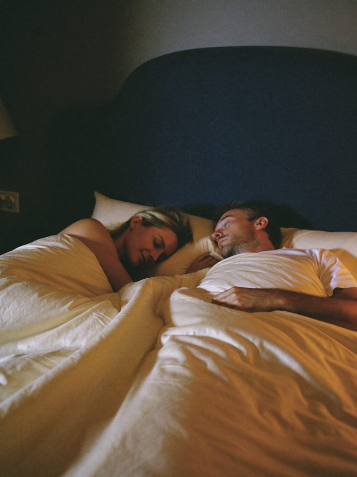 One partner asleep, the other on top of the covers